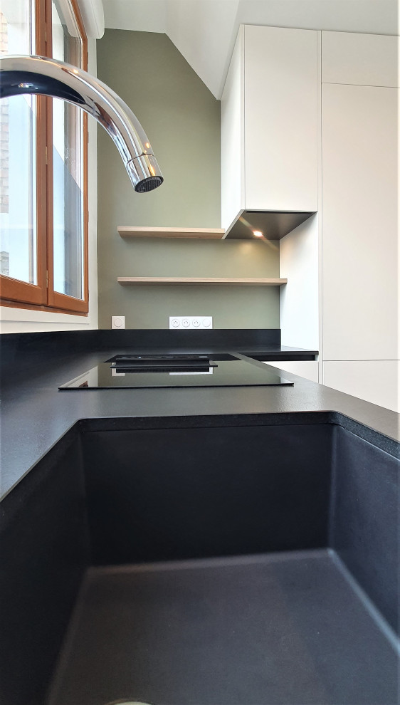 Foto på ett mycket stort funkis svart linjärt kök med öppen planlösning, med en integrerad diskho, släta luckor, vita skåp, granitbänkskiva, svart stänkskydd, integrerade vitvaror, cementgolv, en köksö och grått golv