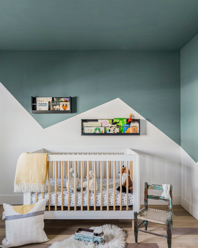 Foto de habitación de bebé neutra actual con paredes verdes, suelo de madera en tonos medios y suelo marrón