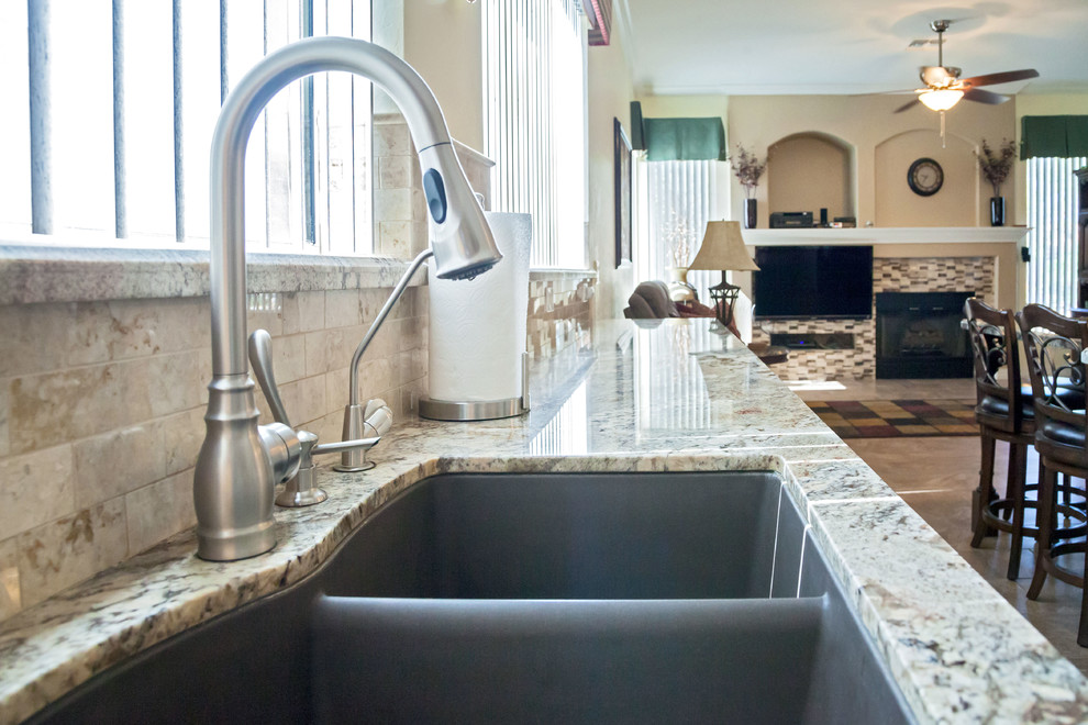 Open concept kitchen - transitional galley porcelain tile open concept kitchen idea in Phoenix with an undermount sink, raised-panel cabinets, dark wood cabinets, granite countertops, beige backsplash, stone tile backsplash, stainless steel appliances and an island