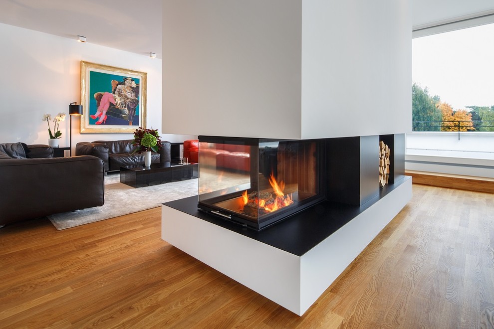 Inspiration for a large contemporary open concept family room in Berlin with a library, white walls, medium hardwood floors, a wood stove, a concrete fireplace surround, no tv and beige floor.