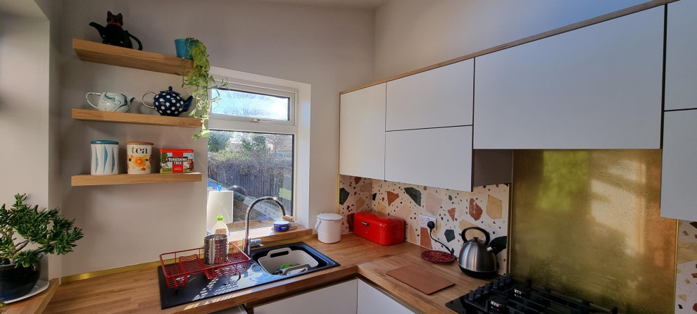 Inspiration for a medium sized scandinavian u-shaped kitchen/diner in Other with a single-bowl sink, flat-panel cabinets, white cabinets, wood worktops, multi-coloured splashback, ceramic splashback, black appliances, ceramic flooring, a breakfast bar, black floors, brown worktops and a drop ceiling.