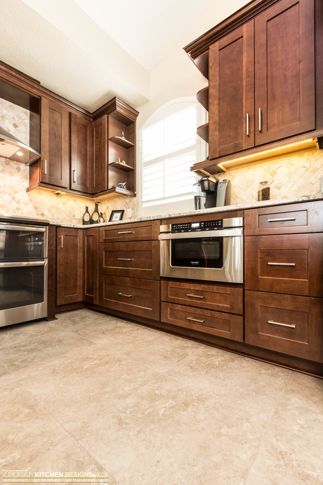 This is an example of a small traditional u-shaped eat-in kitchen in Orlando with an undermount sink, shaker cabinets, dark wood cabinets, granite benchtops, beige splashback, stone tile splashback, porcelain floors, stainless steel appliances and a peninsula.