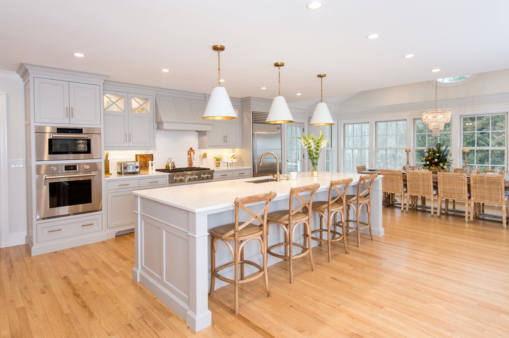 Beach style galley eat-in kitchen in Boston with an undermount sink, shaker cabinets, grey cabinets, stainless steel appliances, light hardwood floors, with island, beige floor and white benchtop.