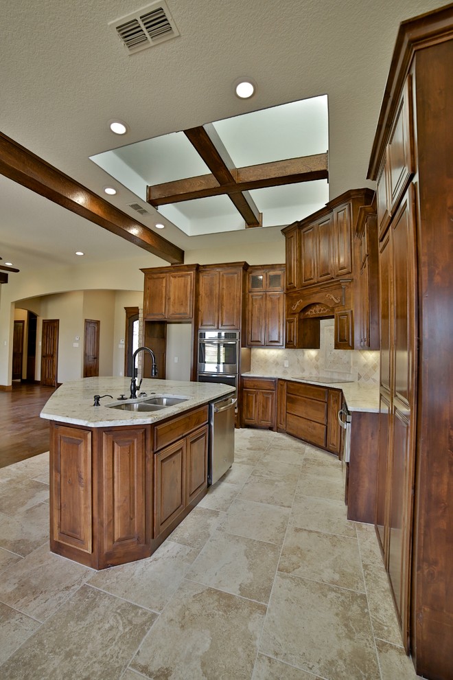 Inspiration for a mid-sized rustic l-shaped porcelain tile eat-in kitchen remodel in Dallas with an undermount sink, raised-panel cabinets, medium tone wood cabinets, granite countertops, beige backsplash, stone tile backsplash, stainless steel appliances and an island