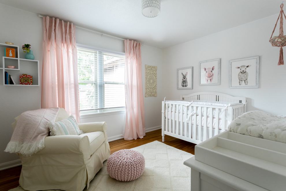 Design ideas for a traditional nursery for girls in Austin with white walls, medium hardwood floors and brown floor.