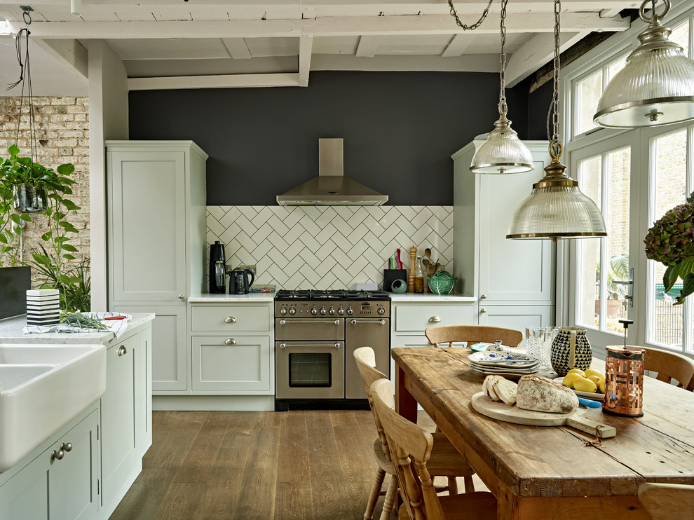 Inspiration for a large scandinavian u-shaped eat-in kitchen in London with a farmhouse sink, green cabinets, marble benchtops, medium hardwood floors, brown floor, white benchtop, shaker cabinets, white splashback, subway tile splashback and stainless steel appliances.