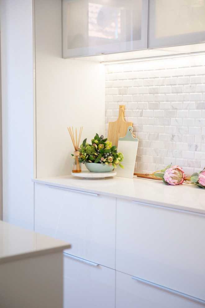 Foto på ett mellanstort vintage vit kök, med en undermonterad diskho, vita skåp, marmorbänkskiva, vitt stänkskydd, stänkskydd i marmor, vita vitvaror, bambugolv, en köksö och brunt golv
