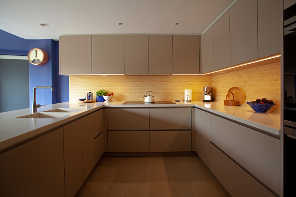 Design ideas for a small contemporary u-shaped eat-in kitchen in Hampshire with an integrated sink, flat-panel cabinets, beige cabinets, solid surface benchtops, timber splashback, panelled appliances, ceramic floors, no island, beige floor and beige benchtop.