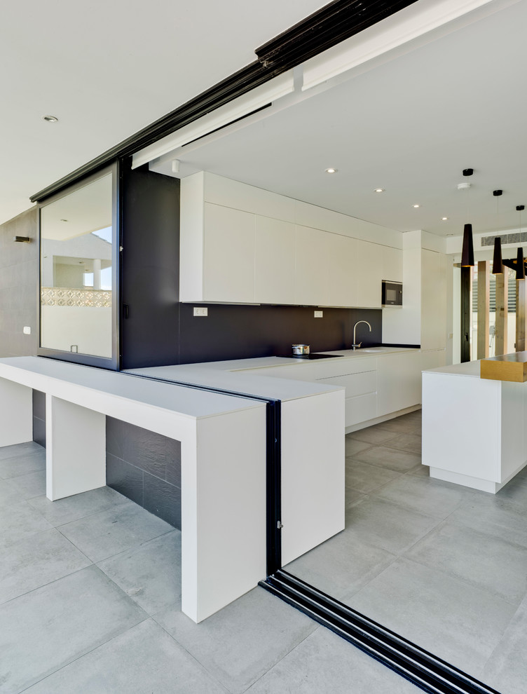 Inspiration for a contemporary l-shaped open plan kitchen in Other with an integrated sink, flat-panel cabinets, white cabinets, black splashback, panelled appliances, ceramic floors, with island, grey floor and white benchtop.