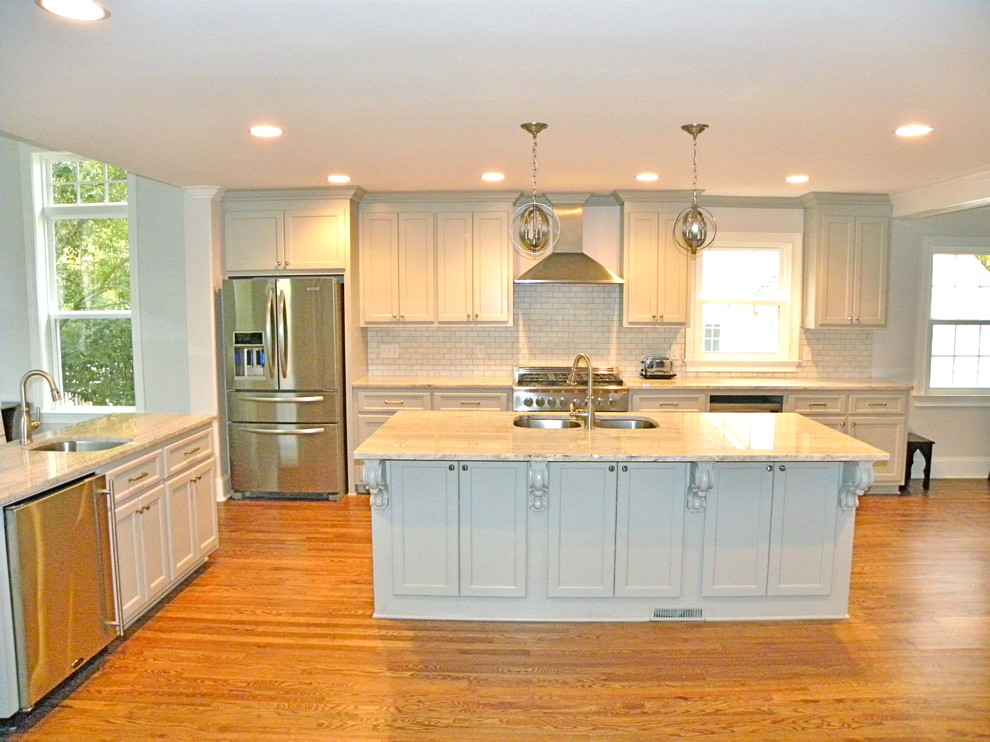 Inspiration for a large transitional l-shaped light wood floor and brown floor eat-in kitchen remodel with a double-bowl sink, recessed-panel cabinets, white cabinets, white backsplash, ceramic backsplash, stainless steel appliances and two islands