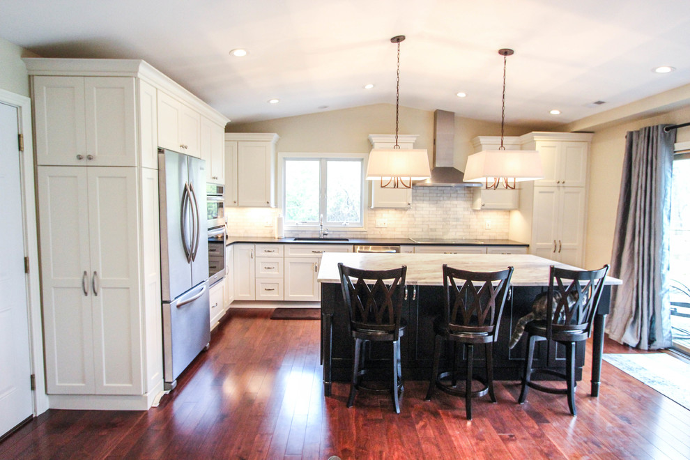 Eat-in kitchen - mid-sized transitional l-shaped medium tone wood floor eat-in kitchen idea in Cincinnati with an undermount sink, recessed-panel cabinets, white cabinets, quartzite countertops, white backsplash, subway tile backsplash, stainless steel appliances and an island