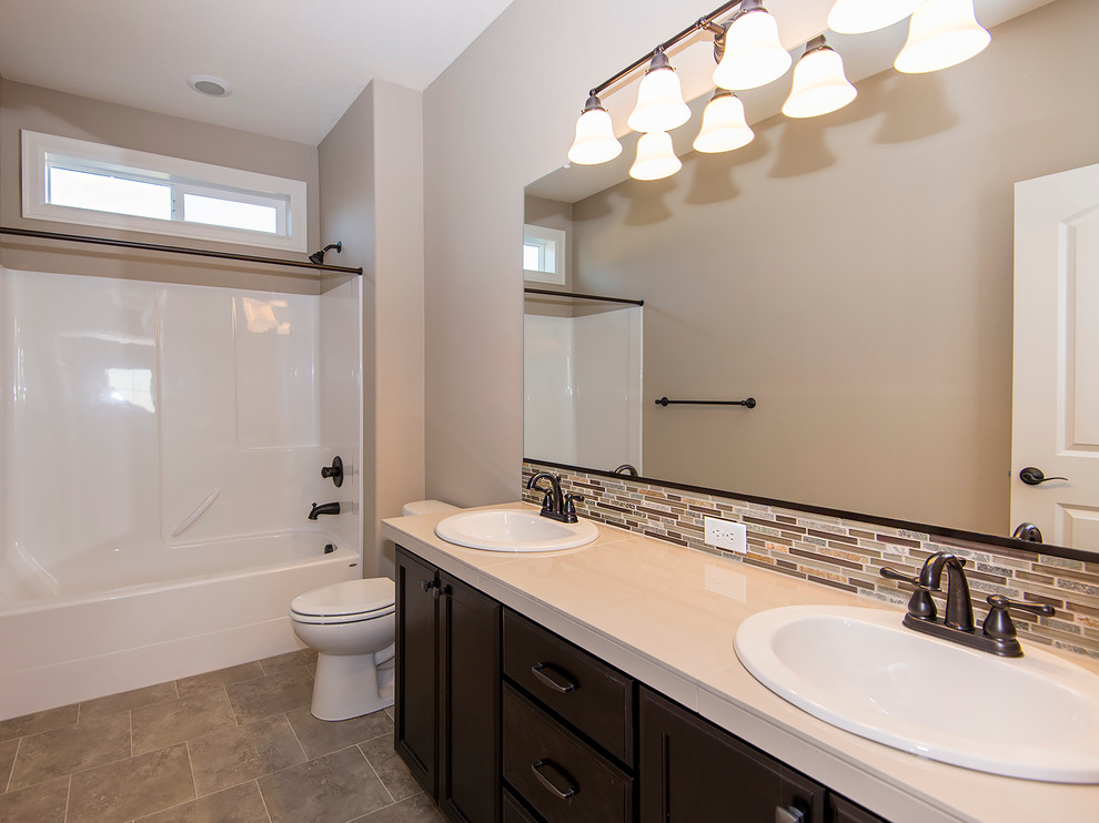 Inspiration for a mid-sized transitional bathroom in Portland with a drop-in sink, recessed-panel cabinets, dark wood cabinets, tile benchtops, an alcove tub, a shower/bathtub combo, beige tile, porcelain tile and porcelain floors.
