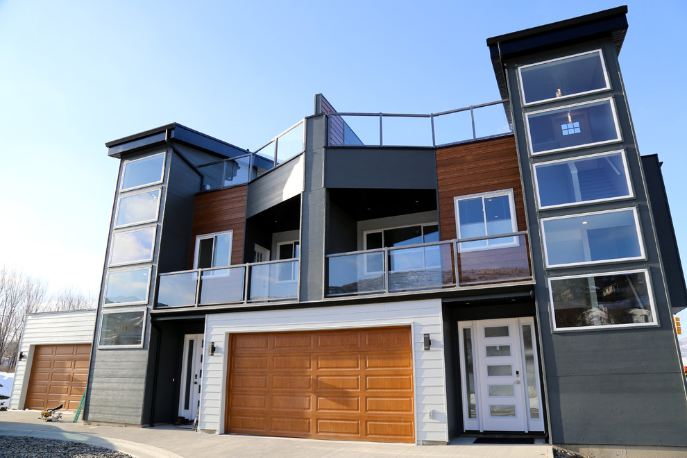 Mid-sized modern two-storey grey duplex exterior in Other with concrete fiberboard siding, a flat roof and a mixed roof.
