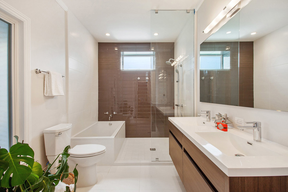 Photo of a mid-sized contemporary master bathroom in San Francisco with flat-panel cabinets, dark wood cabinets, an alcove tub, a shower/bathtub combo, a two-piece toilet, brown tile, white tile, glass tile, white walls, a trough sink and granite benchtops.