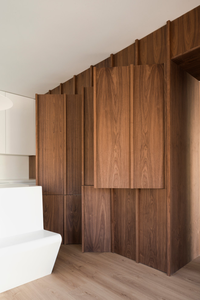 Cette image montre une petite armoire encastrée nordique en bois brun neutre avec un placard avec porte à panneau surélevé, un sol en bois brun, un sol marron et un plafond décaissé.