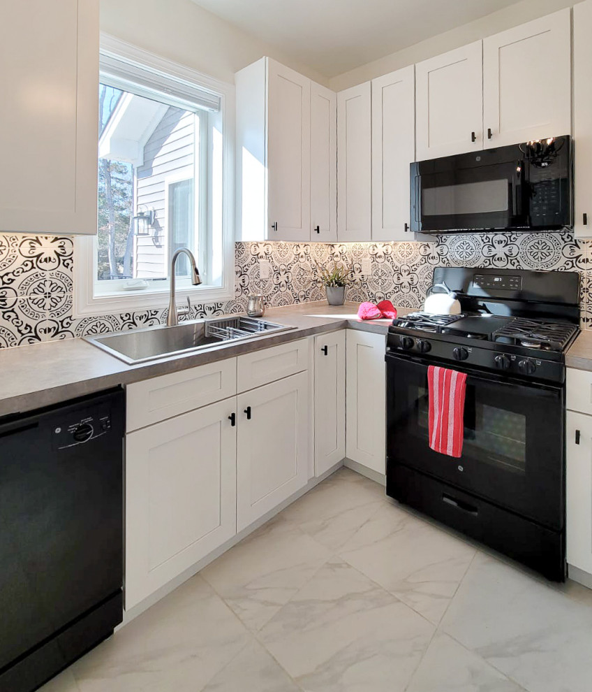 Exempel på ett avskilt, litet medelhavsstil grå grått u-kök, med en nedsänkt diskho, skåp i shakerstil, vita skåp, laminatbänkskiva, svart stänkskydd, stänkskydd i keramik, svarta vitvaror, klinkergolv i porslin och vitt golv