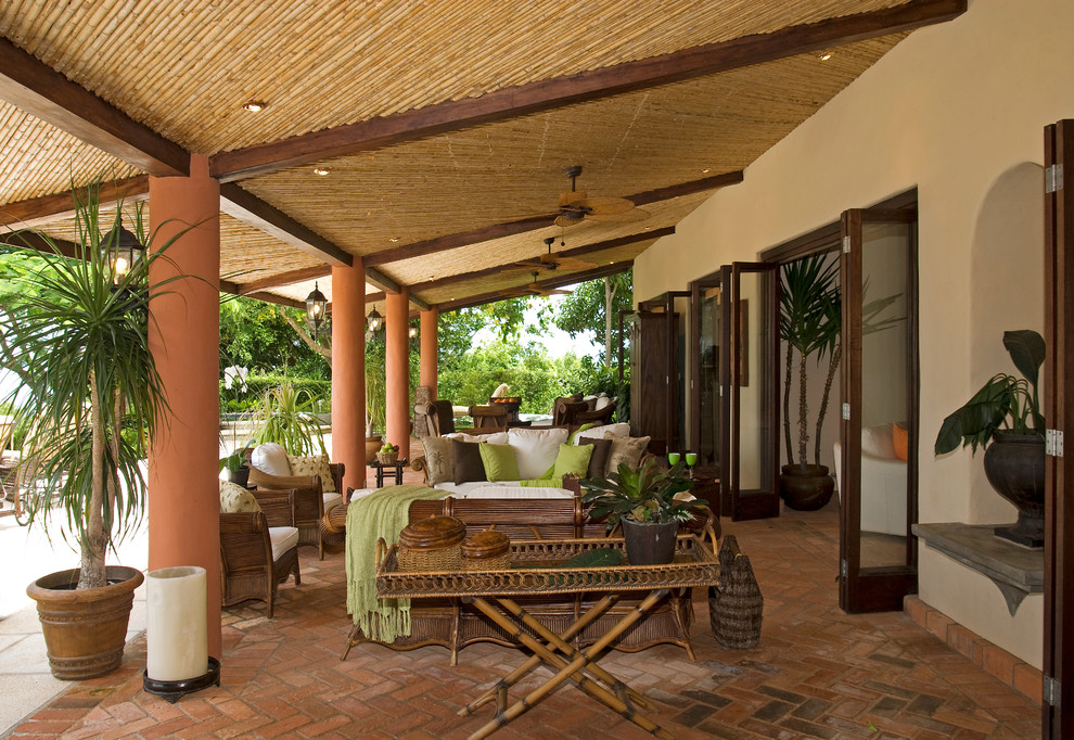 This is an example of a tropical patio in Other with brick pavers and a roof extension.