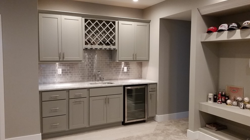 Inspiration for a mid-sized arts and crafts single-wall wet bar in St Louis with an undermount sink, shaker cabinets, grey cabinets, marble benchtops, grey splashback, metal splashback, carpet and beige floor.