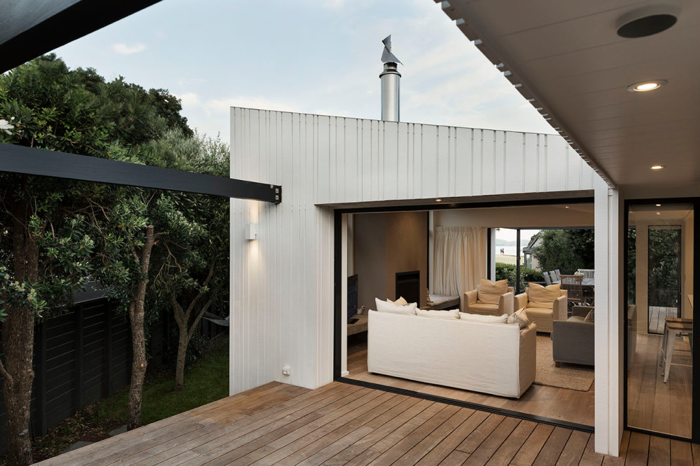 Photo of a mid-sized beach style one-storey white exterior in Auckland with wood siding.