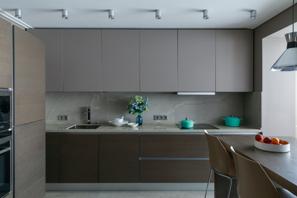 This is an example of a mid-sized contemporary l-shaped kitchen in Moscow with an undermount sink, flat-panel cabinets, grey cabinets, solid surface benchtops, grey splashback, porcelain splashback, porcelain floors, no island, grey floor, stainless steel appliances and beige benchtop.