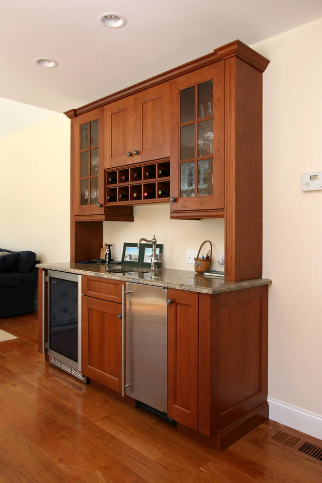 Mid-sized traditional single-wall home bar in Boston with an undermount sink, glass-front cabinets, medium wood cabinets, granite benchtops and medium hardwood floors.