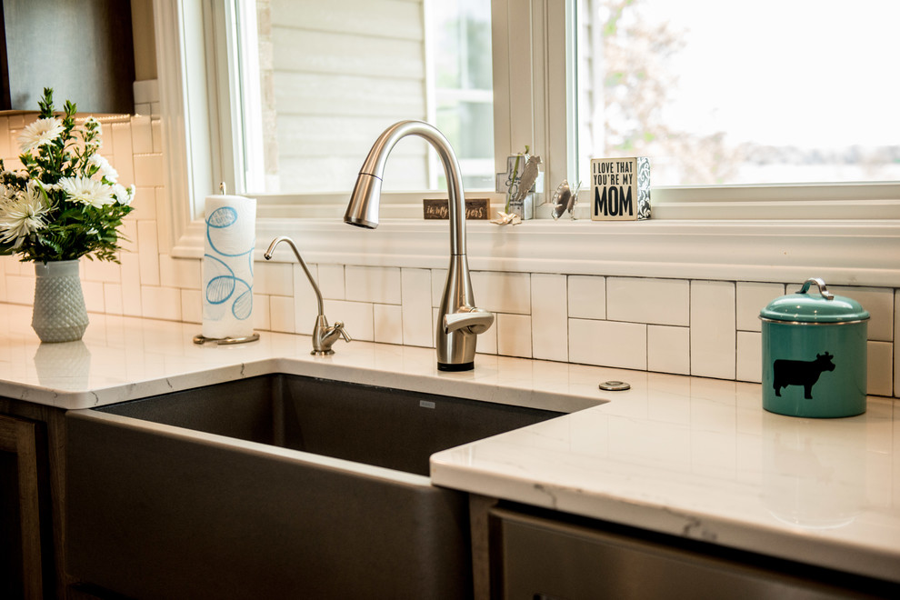 Large transitional l-shaped vinyl floor and multicolored floor open concept kitchen photo with a farmhouse sink, shaker cabinets, gray cabinets, quartz countertops, white backsplash, subway tile backsplash, stainless steel appliances, an island and white countertops