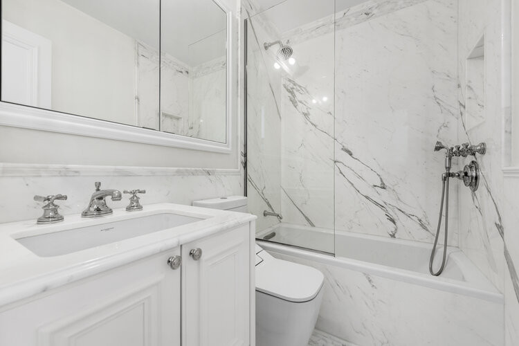 Design ideas for a mid-sized transitional bathroom in New York with furniture-like cabinets, white cabinets, an alcove tub, a shower/bathtub combo, a bidet, white tile, marble, white walls, marble floors, a drop-in sink, marble benchtops, white floor, an open shower, white benchtops, a single vanity and a freestanding vanity.