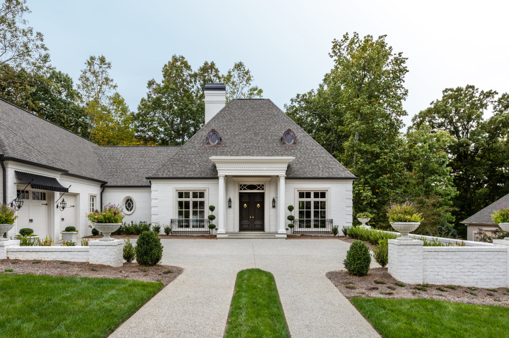 Example of a large transitional white two-story brick house exterior design with a hip roof and a shingle roof