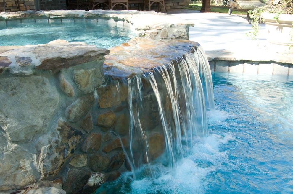 This is an example of a large arts and crafts backyard custom-shaped natural pool in Other with a hot tub and natural stone pavers.