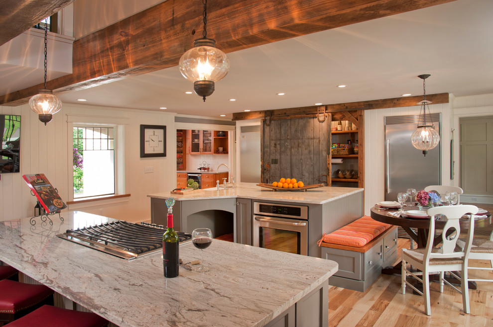 This is an example of a large eclectic u-shaped open plan kitchen in Manchester with a farmhouse sink, flat-panel cabinets, grey cabinets, granite benchtops, stainless steel appliances, light hardwood floors and multiple islands.