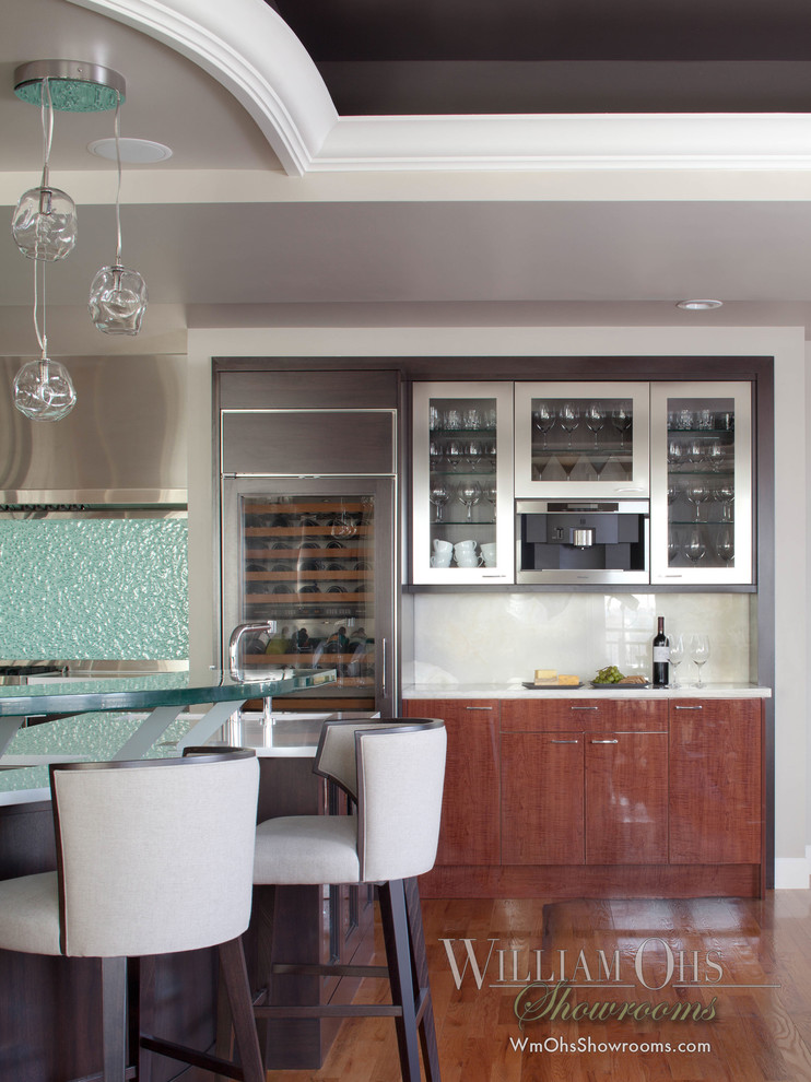 Example of a transitional l-shaped eat-in kitchen design in Denver with a drop-in sink, beaded inset cabinets, brown cabinets, quartz countertops, glass sheet backsplash and stainless steel appliances