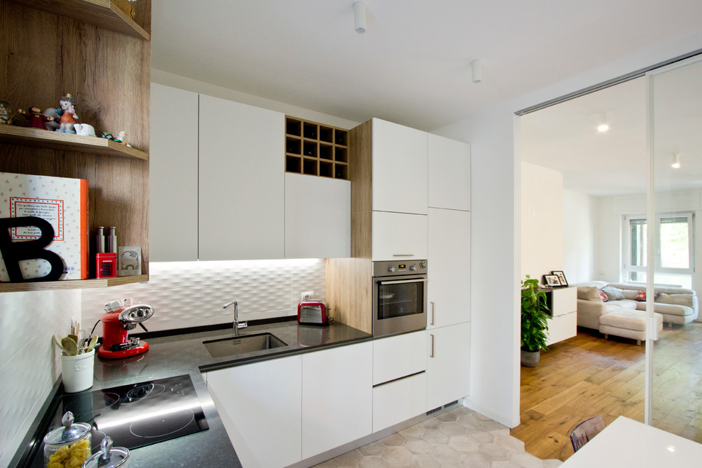 Mid-sized contemporary l-shaped open plan kitchen in Milan with an undermount sink, flat-panel cabinets, white cabinets, quartz benchtops, white splashback, porcelain splashback, stainless steel appliances, porcelain floors, no island, beige floor and grey benchtop.