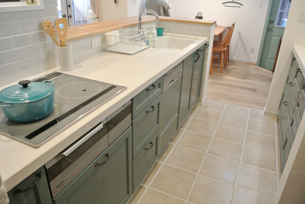 Mid-sized country galley eat-in kitchen in Nagoya with an undermount sink, flat-panel cabinets, white cabinets, tile benchtops, white splashback, subway tile splashback, stainless steel appliances, terra-cotta floors and a peninsula.