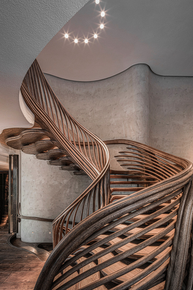 Стильный дизайн: большая винтовая лестница в стиле фьюжн с деревянными ступенями и деревянными перилами - последний тренд
