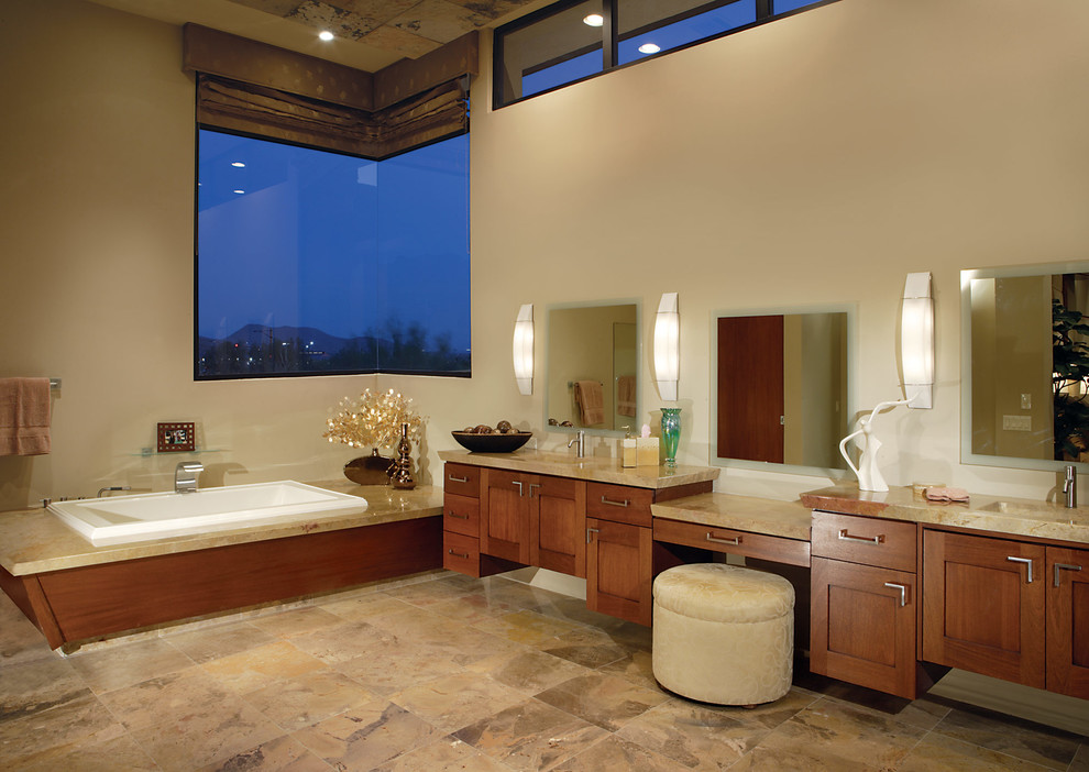 Example of a large trendy multicolored tile marble floor and beige floor drop-in bathtub design in Phoenix with an integrated sink, recessed-panel cabinets, medium tone wood cabinets, granite countertops and beige walls