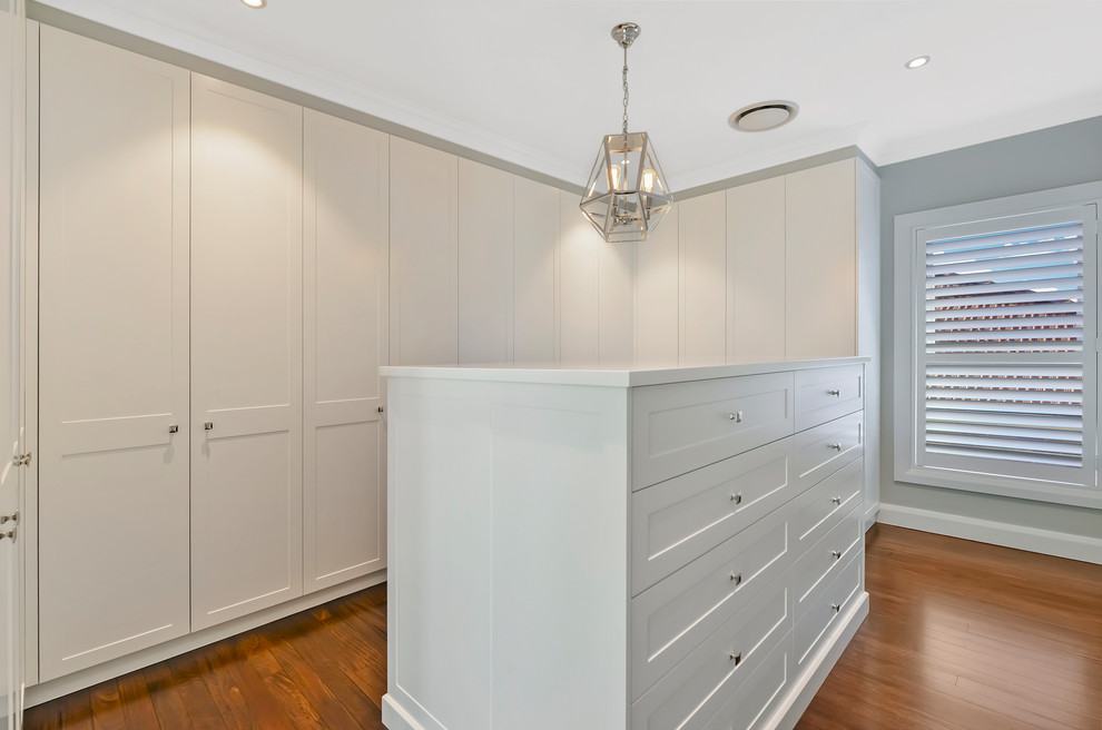 Inspiration for a large contemporary gender-neutral dressing room in Sydney with recessed-panel cabinets, white cabinets, brown floor and dark hardwood floors.