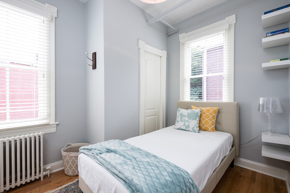 Photo of a transitional guest bedroom in DC Metro with blue walls, medium hardwood floors and brown floor.