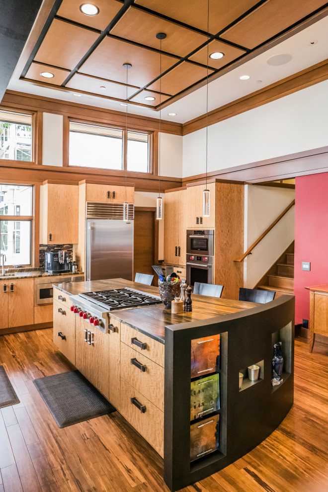 Example of a trendy u-shaped medium tone wood floor and brown floor kitchen design in Seattle with flat-panel cabinets, medium tone wood cabinets, stainless steel appliances, an island and brown countertops