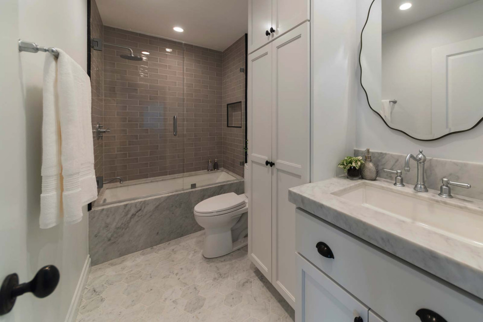 Modern inredning av ett stort badrum, med vita skåp, ett badkar i en alkov, marmorgolv, ett undermonterad handfat, grått golv och dusch med gångjärnsdörr