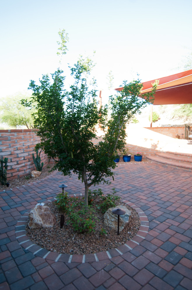 Mid-sized backyard patio in Phoenix with brick pavers and an awning.