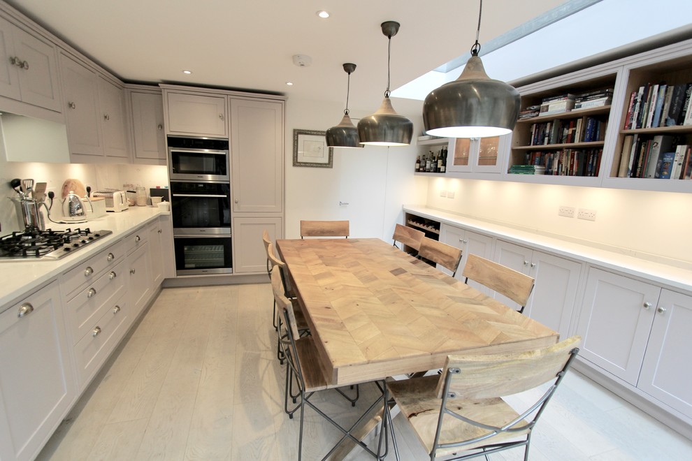 Inspiration for a mid-sized contemporary single-wall eat-in kitchen in London with a drop-in sink, shaker cabinets, purple cabinets, solid surface benchtops, white splashback, stainless steel appliances, medium hardwood floors, no island, brown floor and white benchtop.