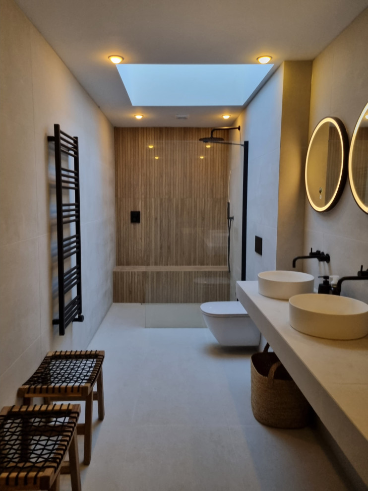 Пример оригинального дизайна: большая главная ванная комната в скандинавском стиле с белыми фасадами, японской ванной, открытым душем, инсталляцией, белой плиткой, керамогранитной плиткой, белыми стенами, полом из керамогранита, настольной раковиной, столешницей из плитки, белым полом, белой столешницей, сиденьем для душа, тумбой под две раковины и подвесной тумбой