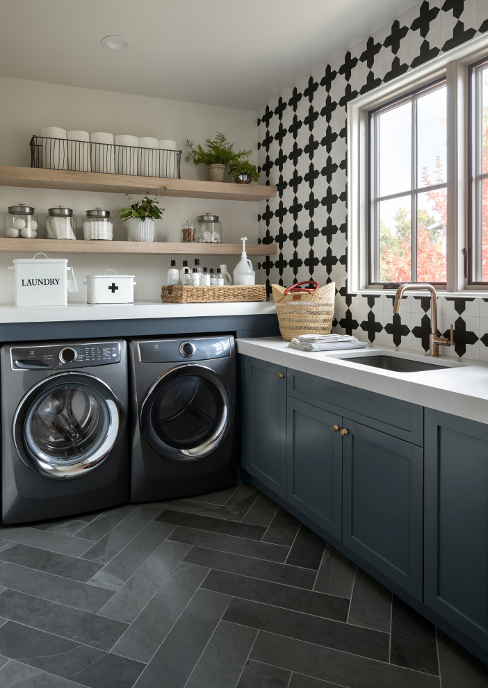 Inspiration for a small country l-shaped dedicated laundry room in Denver with an undermount sink, flat-panel cabinets, blue cabinets, quartzite benchtops, black splashback, cement tile splashback, grey walls, slate floors, a side-by-side washer and dryer, grey floor and white benchtop.