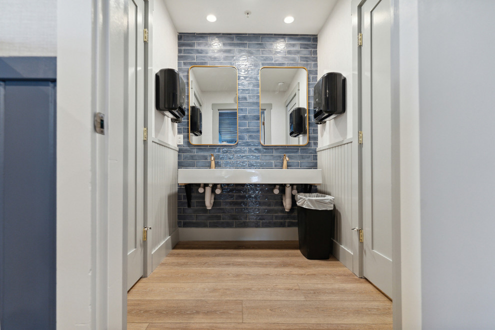 This is an example of a large transitional 3/4 bathroom in Portland Maine with blue tile, ceramic tile, white walls, vinyl floors, a drop-in sink, marble benchtops, brown floor, white benchtops, an enclosed toilet, a double vanity, a built-in vanity, coffered and decorative wall panelling.