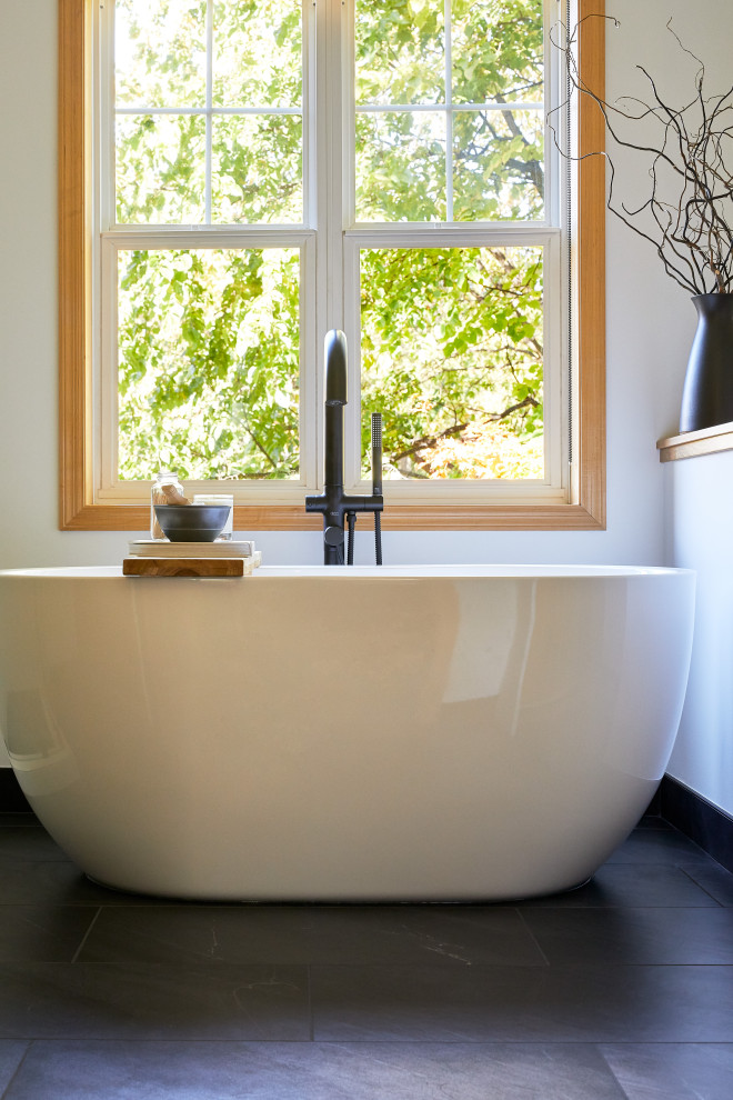 Inspiration for a mid-sized modern master bathroom in Minneapolis with flat-panel cabinets, light wood cabinets, a freestanding tub, ceramic tile, white walls, marble benchtops, black floor, a hinged shower door, white benchtops, a niche, a single vanity and a built-in vanity.