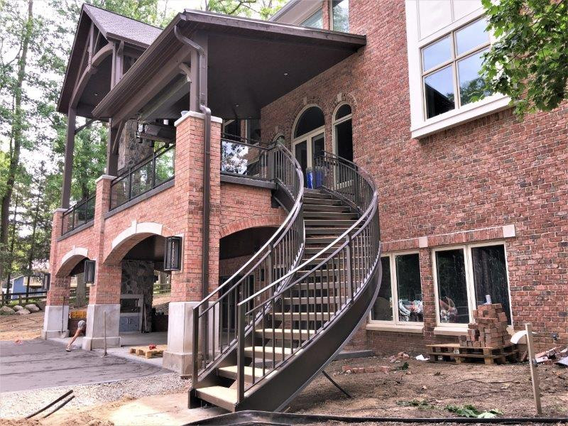 Large traditional wood curved staircase in Detroit with open risers, metal railing and brick walls.