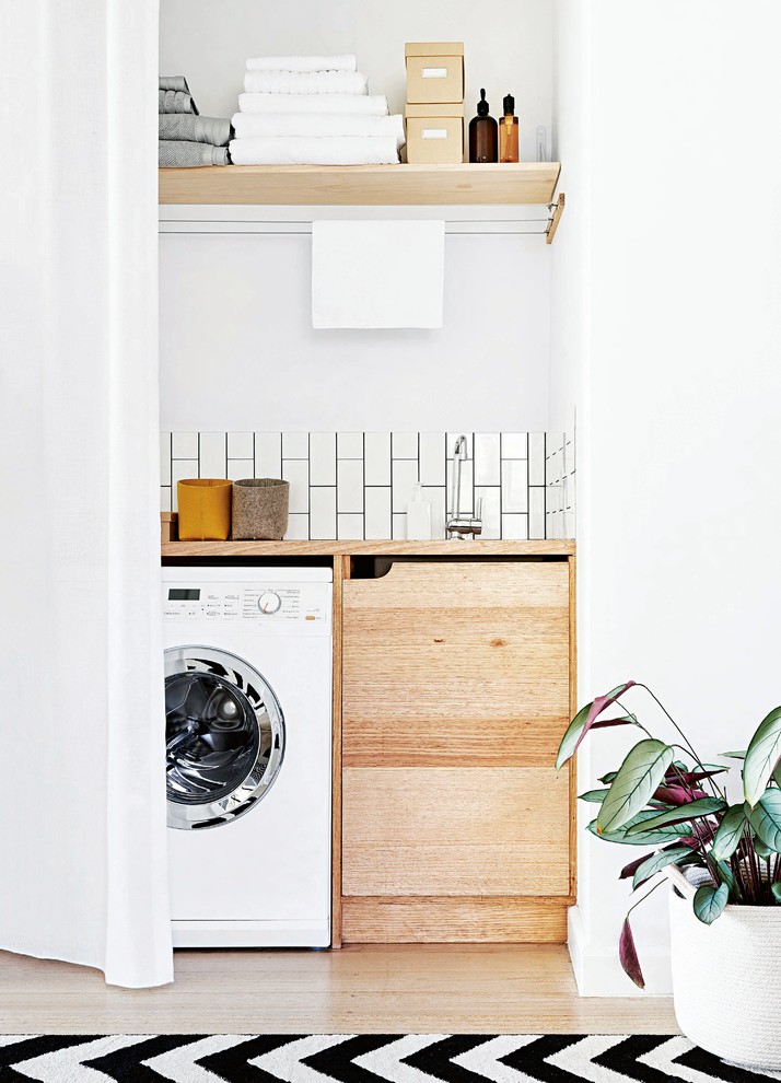 Photo of a small scandinavian single-wall utility room in Melbourne with a drop-in sink, flat-panel cabinets, medium wood cabinets, wood benchtops, white walls, painted wood floors, a side-by-side washer and dryer, white floor and beige benchtop.