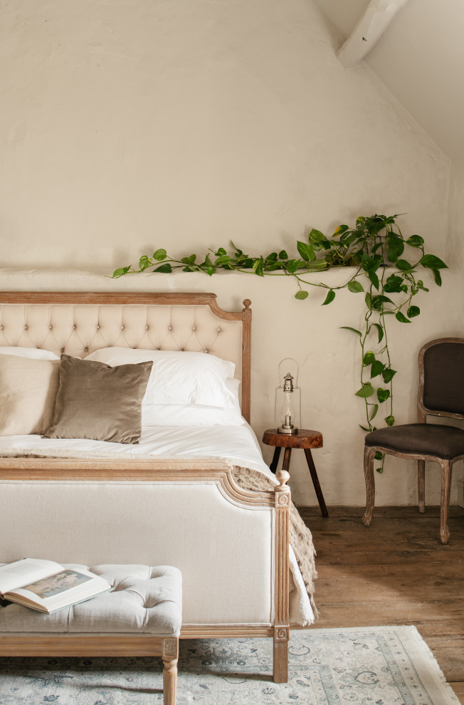 Пример оригинального дизайна: большая хозяйская спальня в стиле кантри с бежевыми стенами, деревянным полом, коричневым полом, балками на потолке и кирпичными стенами без камина