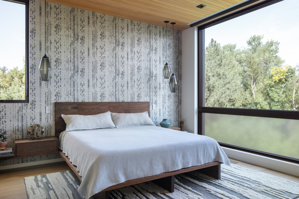 Imagen de dormitorio principal retro con suelo de madera clara, madera y papel pintado