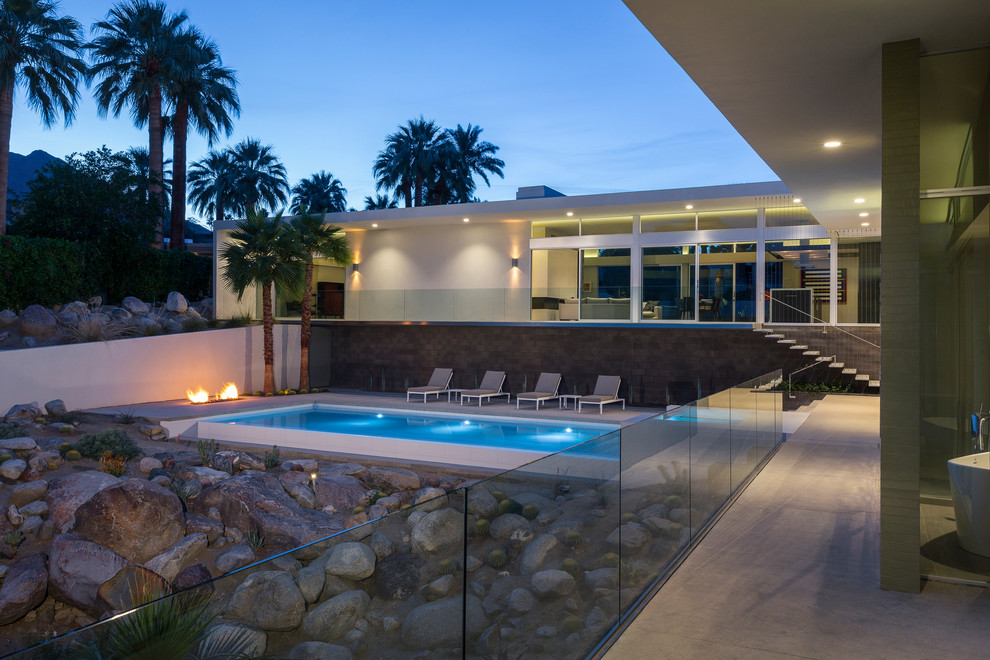 Photo of a large modern backyard patio in Los Angeles with an outdoor kitchen, concrete slab and a roof extension.